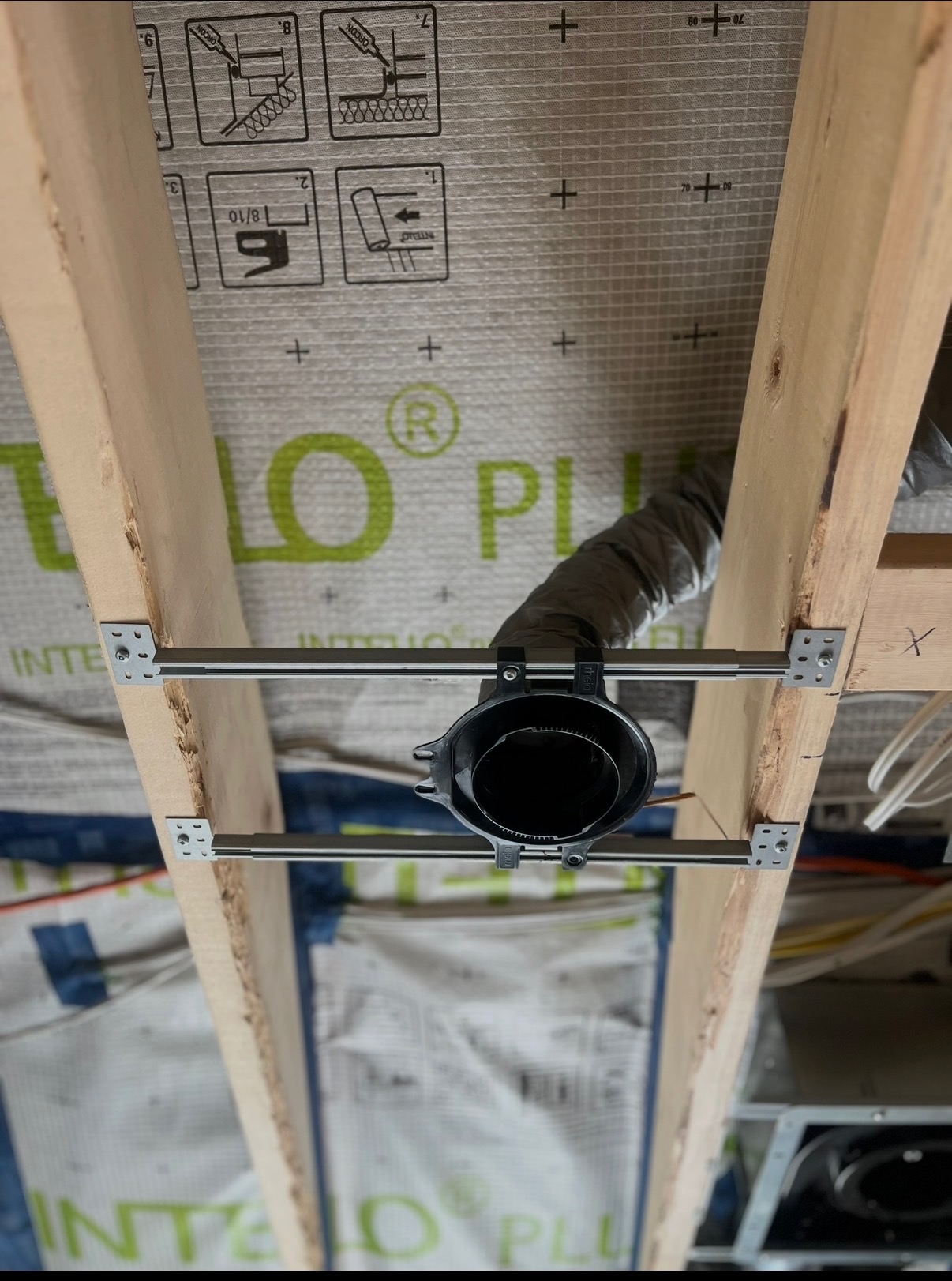 HVAC duct boot mounted between wall studs with flexible duct connection during new home construction