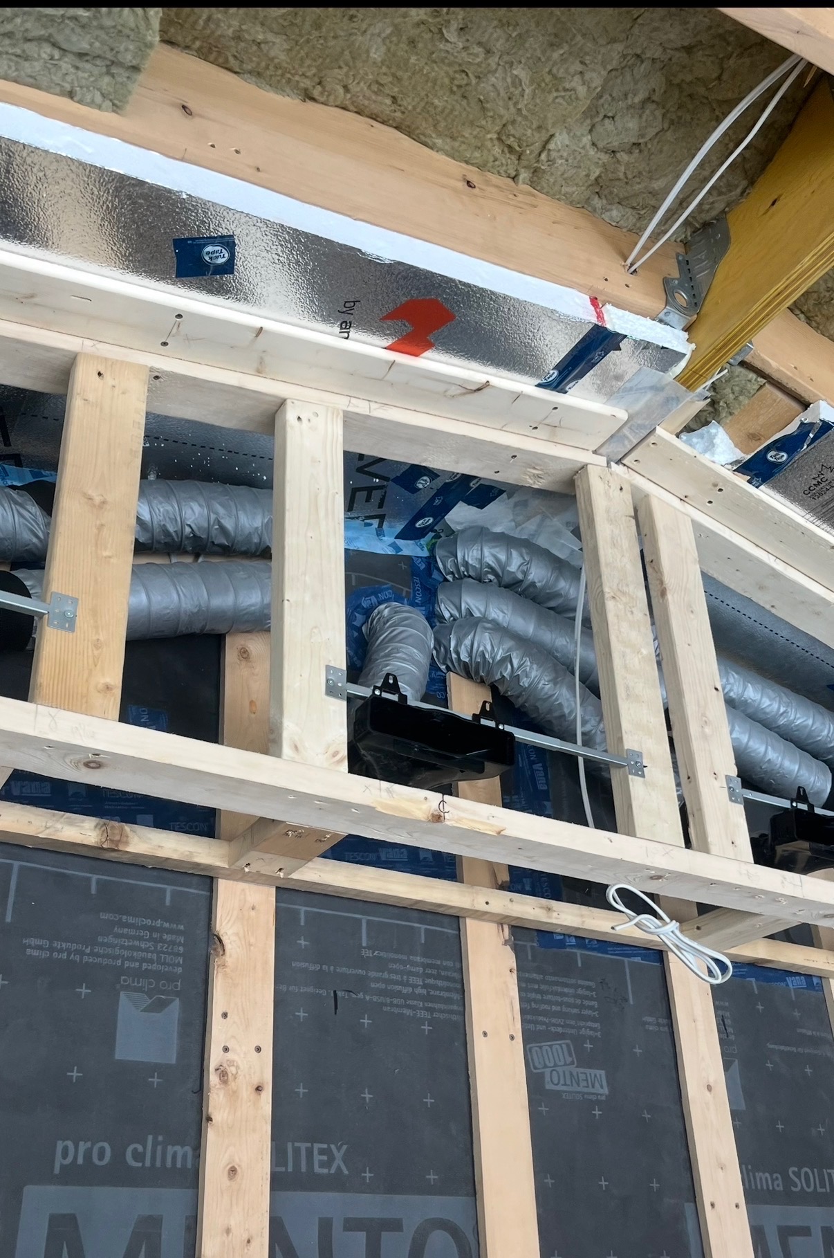Flexible ductwork rough-in installation through wood framing with insulation during new construction in Ottawa