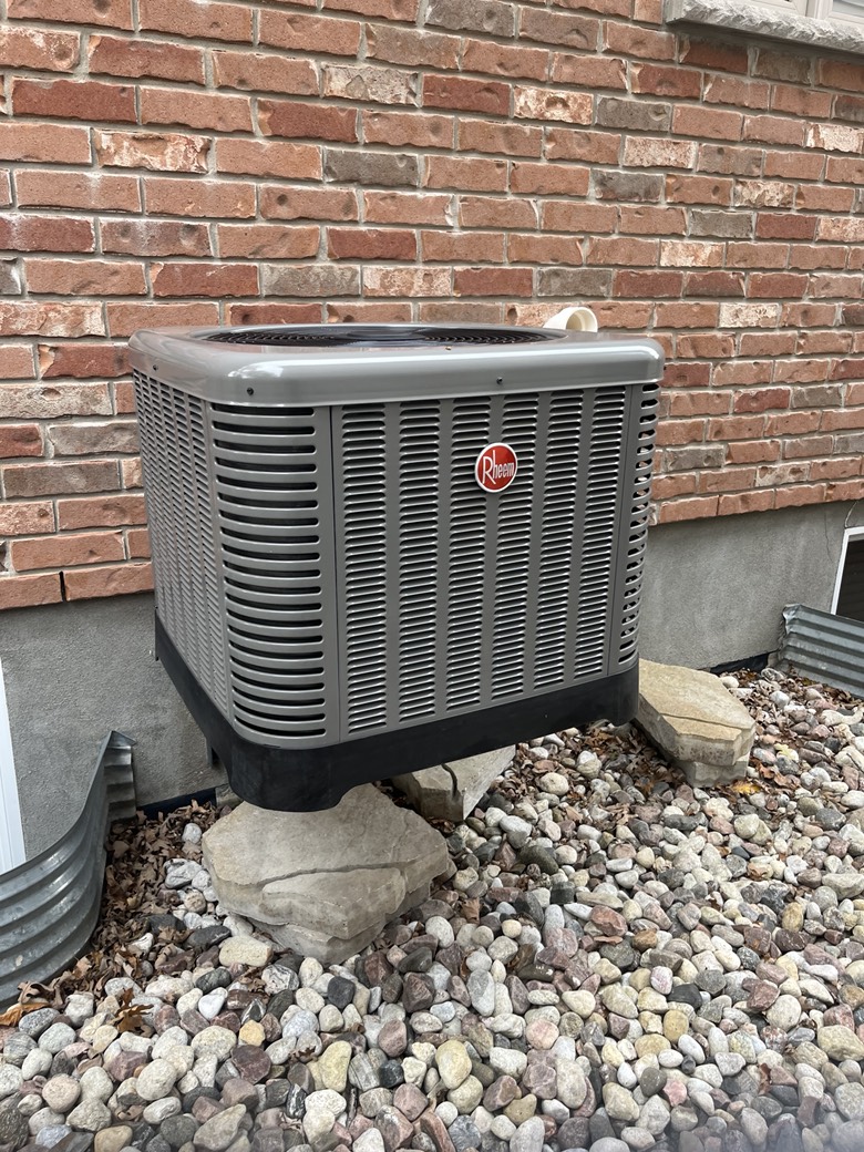 Rheem central air conditioner installed on gravel bed against brick exterior of Ottawa home